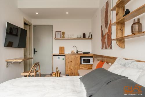 a bedroom with a white bed and a kitchen at Homestay Chất in Hanoi