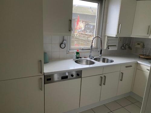 a kitchen with white cabinets and a sink and a window at Woonboot De Witte loosdrechtse plassen in Loosdrecht