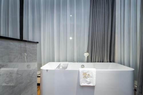 a white bath tub in a room with curtains at Songshan Lake Minshu Villa 