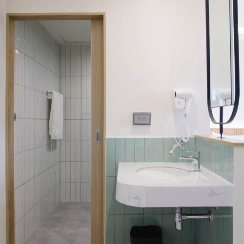 a bathroom with a white sink and a shower at G9 HOTEL Kanchanaburi in Ban Tukkata (1)