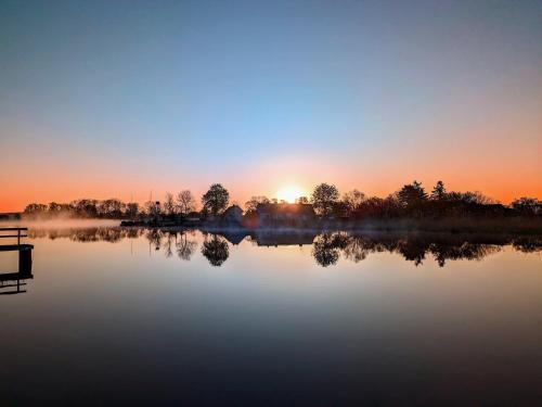 a misty lake with the sun setting in the background at Spacious appartment in Wilhelmshof near Lake in Wilhelmshof