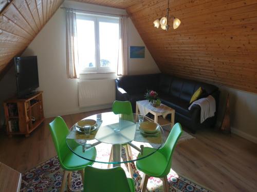 a living room with a glass table and green chairs at Spacious appartment in Wilhelmshof near Lake in Wilhelmshof