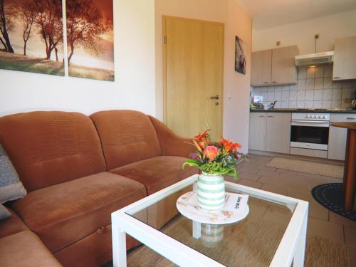 a living room with a couch and a table with a vase of flowers at Spacious appartment in Wilhelmshof near Lake in Wilhelmshof