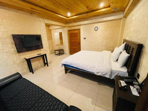 a bedroom with a bed and a tv and a couch at Naran, Rockwood Hotel, in Nārān