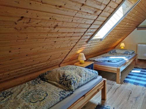 two beds in a room with a wooden wall at Spacious appartment in Wilhelmshof near Lake in Wilhelmshof