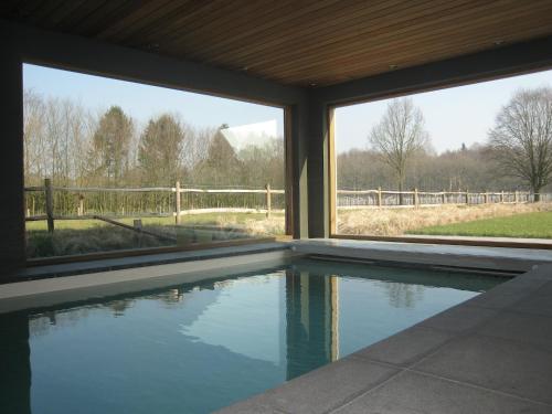 a swimming pool in a house with a view of a fence at Family Farmhouse with Sauna in Beernem