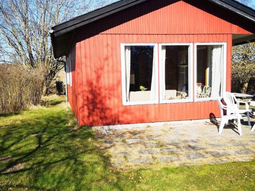 a red house with a white window and a chair at 4 person holiday home in Knebel in Knebel
