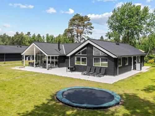 a black house with a trampoline in front of it at 18 person holiday home in Væggerløse in Marielyst