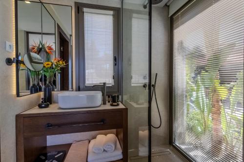 a bathroom with a sink and a shower with a mirror at Maravilla Luxury Living in Kos Town