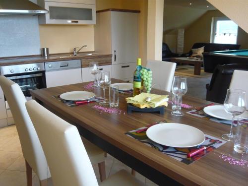 a wooden table with white plates and wine glasses at Pummpälzhof in Bad Salzungen