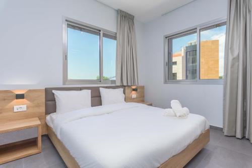 a bedroom with a white bed and two windows at Grey - Elegant Apartments in Awkar in Dbayeh