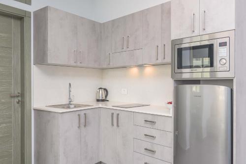 a kitchen with white cabinets and a stainless steel refrigerator at Grey - Elegant Apartments in Awkar in Dbayeh