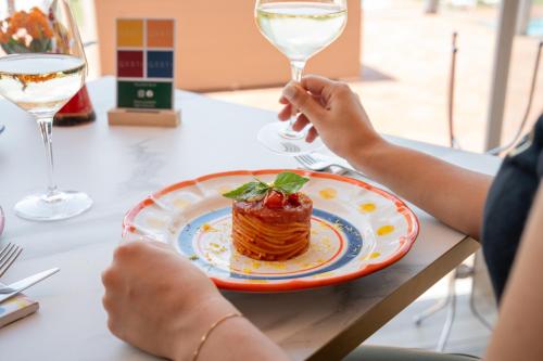 a person holding a glass of wine next to a plate of food at Hotel Boffenigo - The Golden Hour in Costermano sul Garda