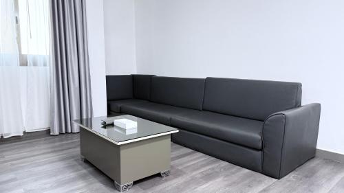 a black couch and a coffee table in a living room at Sunday Sharjah Aparthotel formerly Royal Tulip in Sharjah
