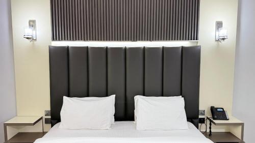 a bedroom with a bed with two pillows at Sunday Sharjah Aparthotel formerly Royal Tulip in Sharjah