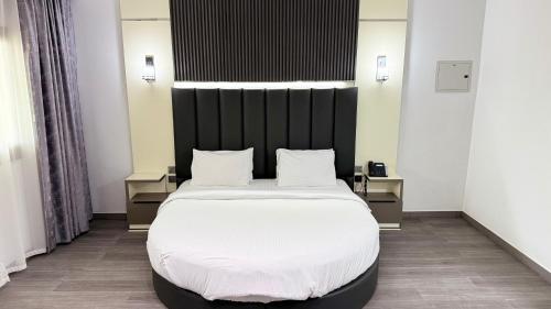 a bedroom with a large bed with a black headboard at Sunday Sharjah Aparthotel formerly Royal Tulip in Sharjah