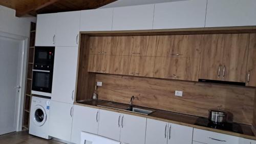 eine Küche mit weißen Schränken und einer Spüle und einem Herd in der Unterkunft Vila Harxhaj 3 in Razëm