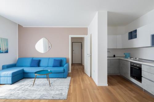 a living room with a blue couch and a kitchen at Hotel Vis à Vis in Trieste