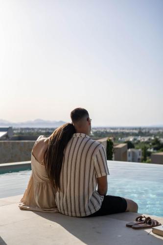 a man and woman sitting on the edge of a swimming pool at Maravilla Luxury Living in Kos Town