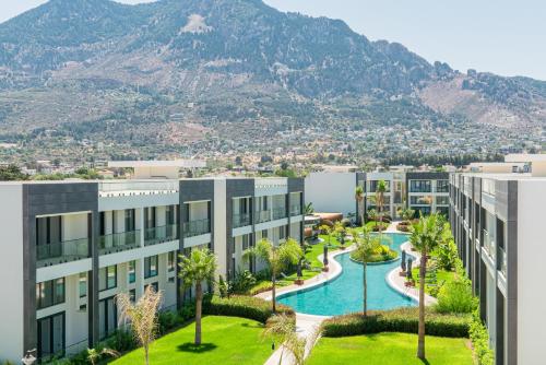 an apartment building with a pool and mountains in the background at Palmera Resort Wellness & SPA in Kérynia