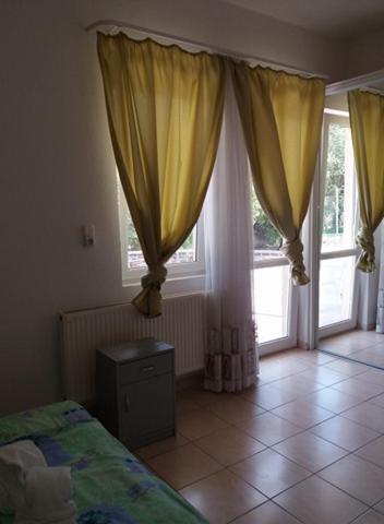 a bedroom with yellow curtains and a bed and two windows at Klassz Apartmanház in Balatonfüred