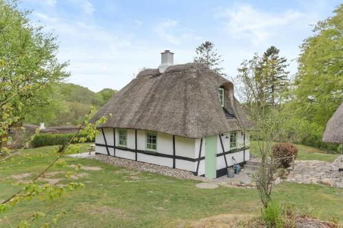 a thatched house with a grass roof at Sheena's Cabin In The Heart Of Hammer Bakker in Vodskov