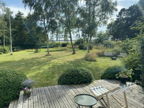 a wooden deck with a table and a bench in a yard at Holiday Home By Avnø Fjord In Front Of The Sea in Vordingborg