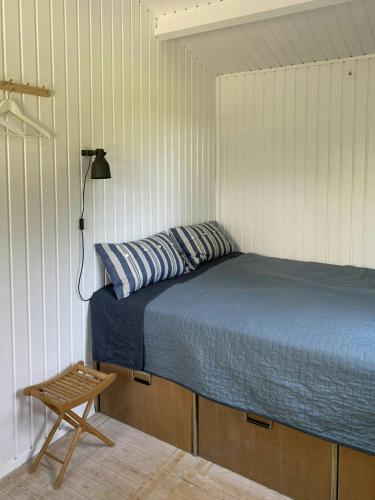 a bedroom with a bed and a wooden stool at Holiday Home By Avnø Fjord In Front Of The Sea in Vordingborg