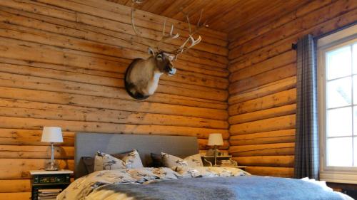 a bedroom with a bed with a deer head on the wall at Historic Hunting Lodge By Lake Øyangen in Hønefoss