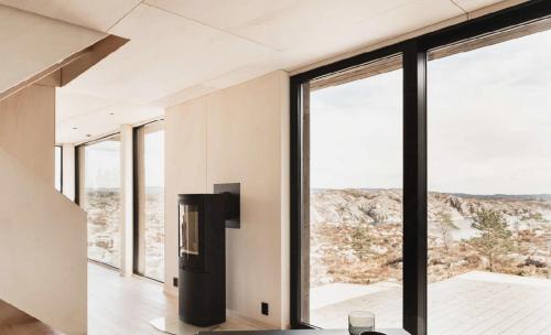 a room with large windows and a black refrigerator at Architect-Designed Cabin Panoramic View in Ervik