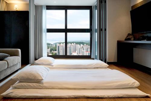 two beds in a room with a large window at The Hotel Sokcho in Sokcho