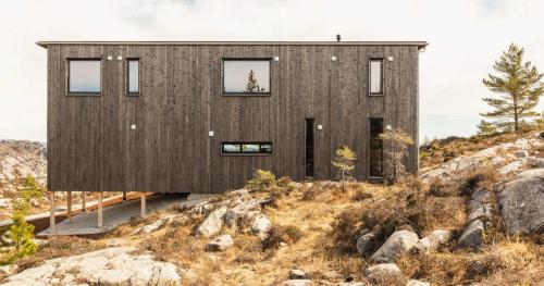 a house on top of a hill with rocks at Architect-Designed Cabin Panoramic View in Ervik
