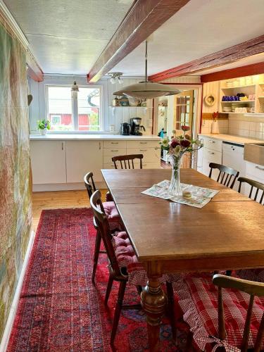 a kitchen with a wooden table with chairs and a vase of flowers at 18Th Century House With Glass Porch In Småland in Söderåkra