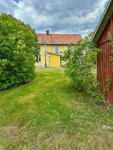 a yellow house with a red fence and a yard at 18Th Century House With Glass Porch In Småland in Söderåkra