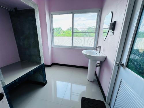 a bathroom with a sink and a shower and a mirror at พี เค ซี รีสอร์ท in Prakhon Chai