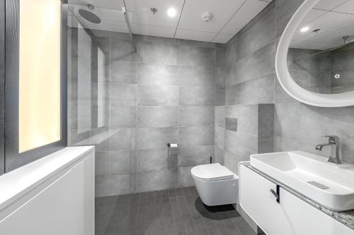 a bathroom with a sink and a toilet and a mirror at Luxury apartment, outstanding view, free parking in Tallinn