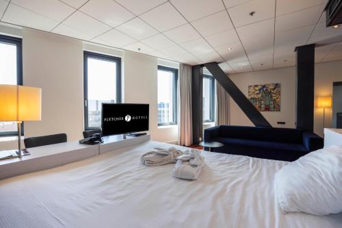 a bedroom with a white bed with a flat screen tv at Fletcher Wellness-Hotel Leiden in Leiden
