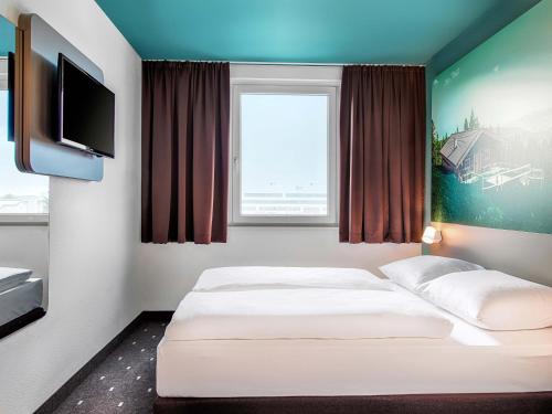 a room with two beds and a tv at B&B Hotel München-Putzbrunn in Putzbrunn