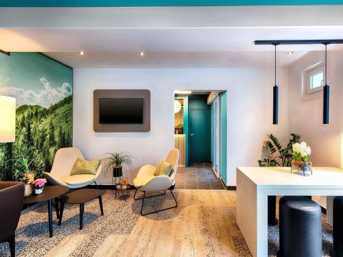 a living room with a table and chairs and a tv at B&B Hotel München-Putzbrunn in Putzbrunn