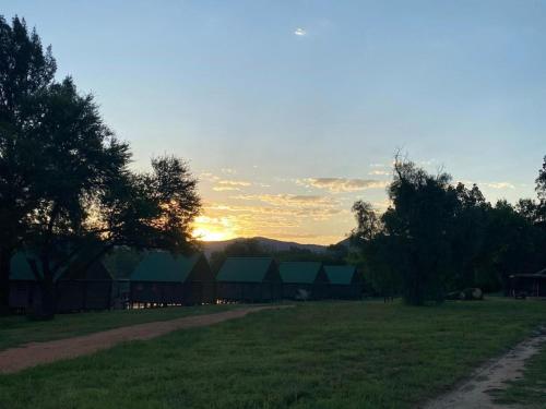 a sunset over a field with trees and buildings at Edge of the Crater in Venterskroon
