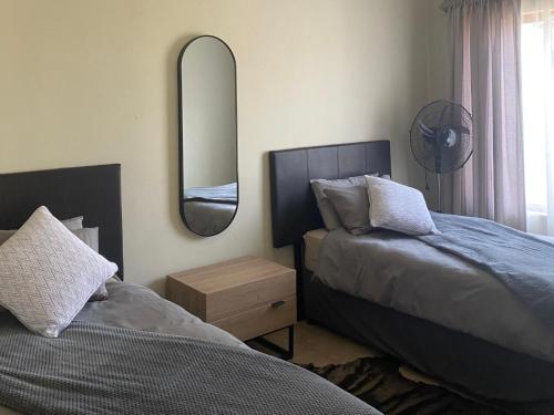 a bedroom with two beds and a mirror on the wall at Edge of the Crater in Venterskroon