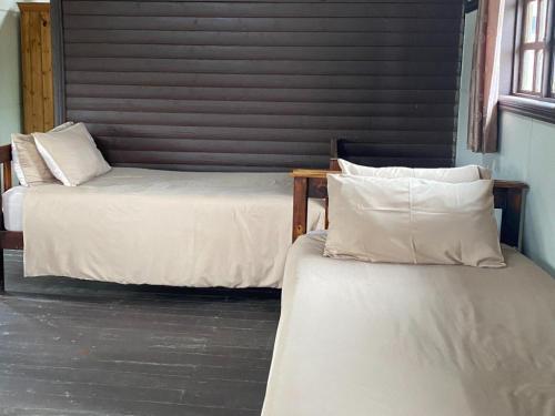 two beds with white sheets and pillows in a room at Edge of the Crater in Venterskroon