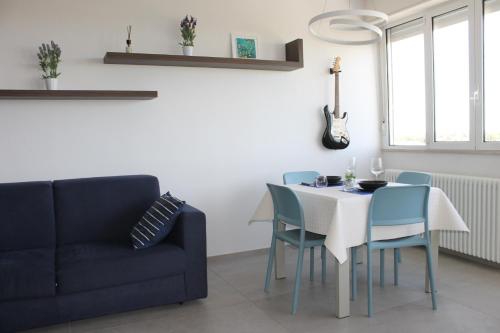 Un comedor con una mesa y sillas y un sofá. en NEWTON30 - Luminoso bilocale in zona servita, en Rávena