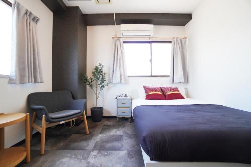 a bedroom with a bed and a chair and a window at Nishiki-en in Osaka