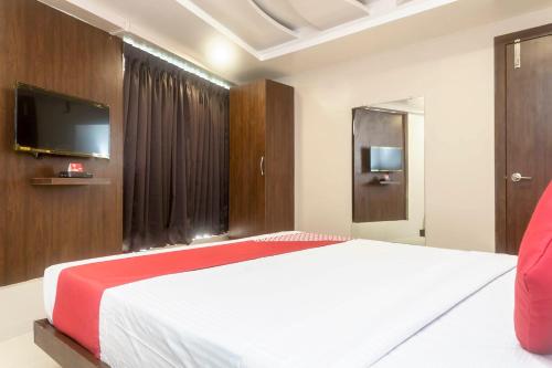 a bedroom with a large bed with a tv on the wall at Hotel O Grand Pune in Pune