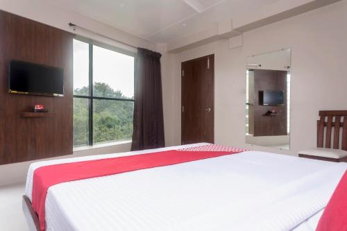 a bedroom with a large bed and a large window at Hotel O Grand Pune in Pune