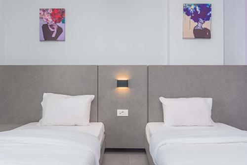 two beds in a hotel room with white pillows at Grey - Elegant Apartments in Awkar in Dbayeh