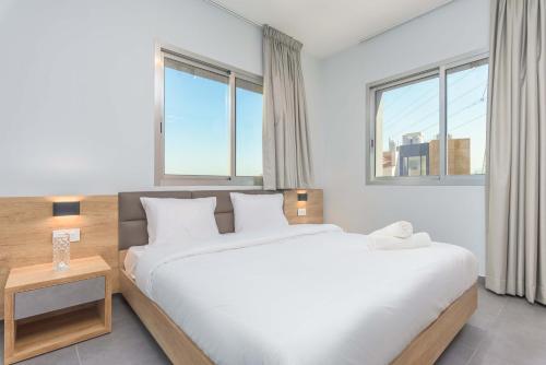 a bedroom with a large bed and two windows at Grey - Elegant Apartments in Awkar in Dbayeh