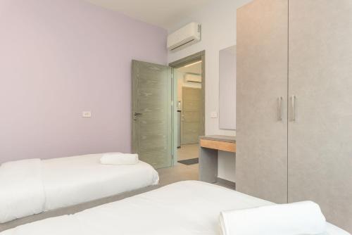 a white bedroom with two beds and a closet at Grey - Elegant Apartments in Awkar in Dbayeh