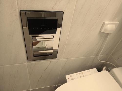 a microwave on a wall in a bathroom with a toilet at The November Stay Guri Station in Guri